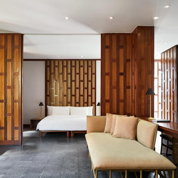 安缦璞瑞度假村的主卧室，配有圆形床、木质屏风和米色沙发。