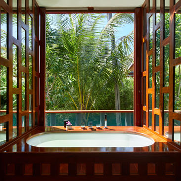 安缦璞瑞度假村的浴室，透过木框玻璃门眺望郁郁葱葱的花园景色。