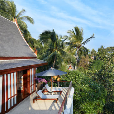 安缦璞瑞度假村别墅露台，配有日光躺椅，俯瞰棕榈树和热带花园。