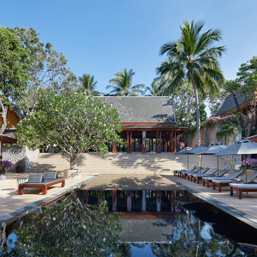 安缦璞瑞度假村的木质建筑坐落于棕榈树和绿植之间，前方有宁静的水道。