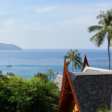 安缦璞瑞度假村的别墅屋顶与远处的海湾和棕榈树相映成趣。