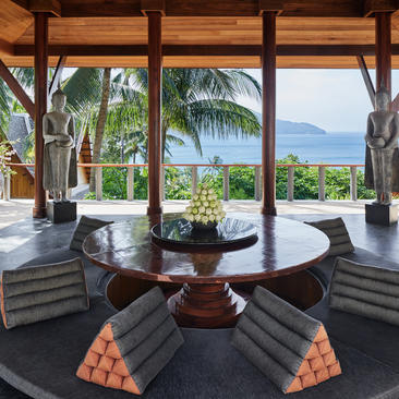 Villa living area at Amanpuri resort with views towards mountains and palm trees.