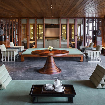 安缦璞瑞度假村宽敞的接待厅，木制展示柜、中央壁炉和现代家具营造出沉静优雅的氛围。