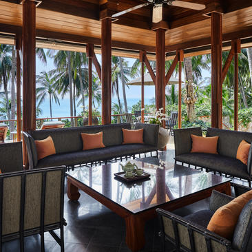 安缦璞瑞度假村的木质别墅内部，配有现代家具、玻璃窗和热带海景。