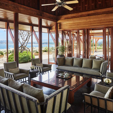 安缦璞瑞度假村宽敞的木质客厅，配有舒适座椅、大窗户和海景。