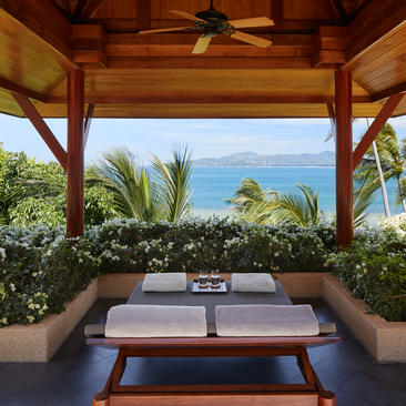 安缦璞瑞度假村的开放式凉亭,面向大海,配有木制长凳和低矮茶几。