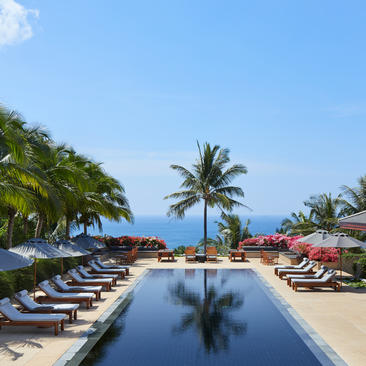 安缦璞瑞度假村的无边泳池，两侧排列着躺椅，周围棕榈树环绕，远眺蔚蓝海景。