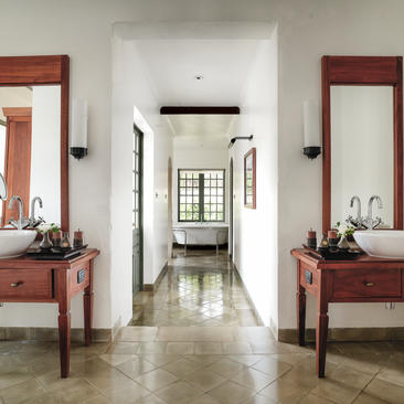 Khan suite basins at Amantaka, with dual wooden vanities and mirrors flanking a central passageway.