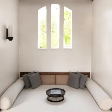 Arched window above a built-in seating nook with cushions and a round table at Amantaka.