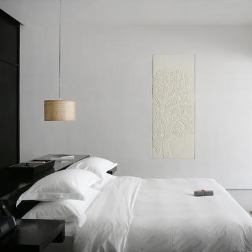 Principal bedroom at Amansara with minimalist décor, pendant light, and wall art.