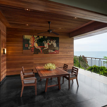 Dining area at Amanoi with wooden walls, table seating for four, and coastal views from the terrace.