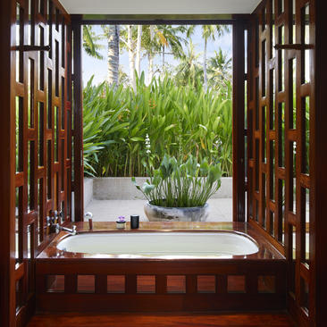 安缦璞瑞度假村的木制窗框景观，窗外可见绿植和露台浴缸。