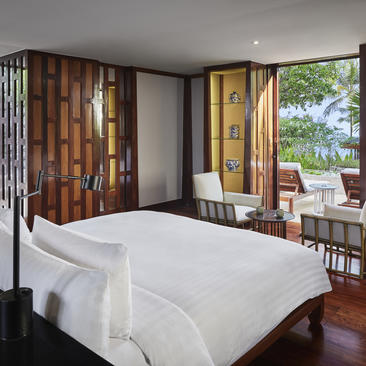 安缦璞瑞度假村的宽敞卧室，配有白色床铺、木质屏风和落地窗，可眺望绿景。