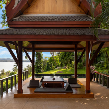 安缦璞瑞度假村宽敞的木制凉亭，配有舒适的座椅，俯瞰绿色景观。