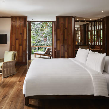 安缦璞瑞度假村的主卧室，设有白色床品、木质家具和通往户外的落地窗。