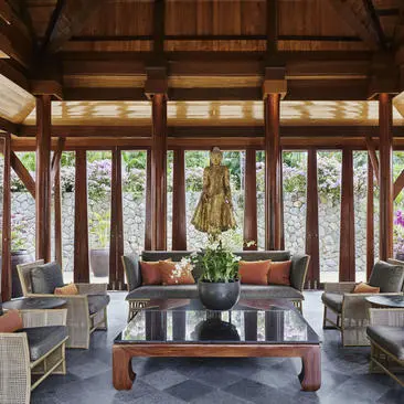 Sala d'attesa con travi in legno e grandi finestre che si affacciano sulla vegetazione tropicale, Amanpuri resort.