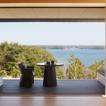 Two ceramic vessels on a wooden deck overlooking a blue bay at Amanemu.