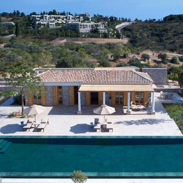 Villa with terracotta roof and plunge pool overlooking turquoise waters at Amanzoe resort, Greece.