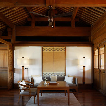 大研安缦度假村的庭院套房内部，展示木梁天花板、传统屏风及简约家具。