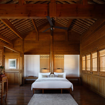 Deluxe Suite at Amandayan with wooden pavilion architecture, central bed, and shoji screens.