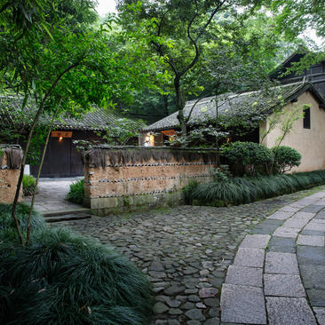 法云安缦度假村的豪华村落套房外观，古树环绕石墙建筑。