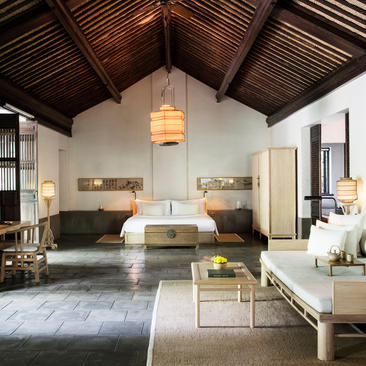 法云安缦度假村豪华村套房的宽敞起居室，配有木质天花板和柔和照明。