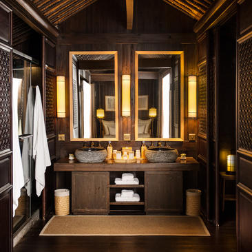Bathroom at Amanfayun with dark wood cabinetry, dual mirrors with brass frames, and warm lighting.
