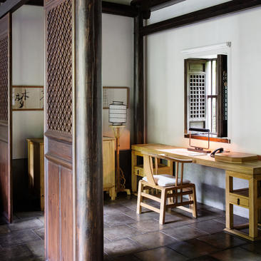 法云安缦度假村套房内部，展示简洁的木质书桌、传统屏风和石墨色地板。