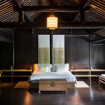 Principal bedroom at Amanfayun villa with wooden bed and dark timber ceiling beams.