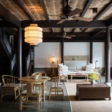 Amanfayun villa living space with wooden beams, pendant lighting, and contemporary furnishings overlooking the landscape.