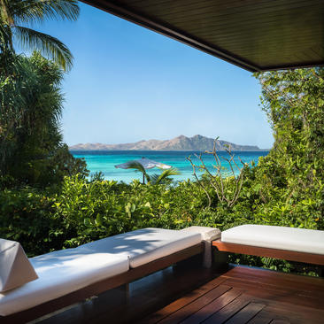 Terrasse en bois d'une casita avec vue sur la baie turquoise à Amanpulo, station balnéaire des Philippines.