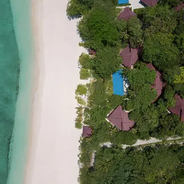 Vista aérea de una villa de tres dormitorios en Amanpulo, rodeada de vegetación tropical junto a aguas turquesas.