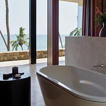 Amanwella suite bathtub with ocean view through floor-to-ceiling windows.
