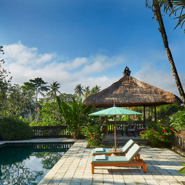 Wooden deck with loungers beside a plunge pool at Amandari, framed by tropical vegetation and a thatched pavilion.