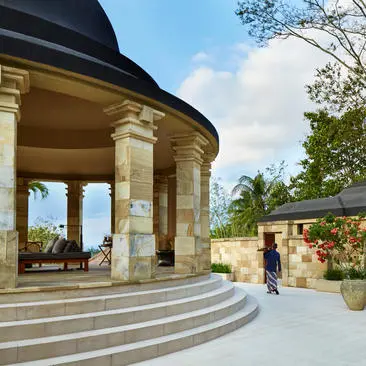 Dalem Jiwo Suite entrance with curved stone pavilion and columns at Amanjiwo resort.