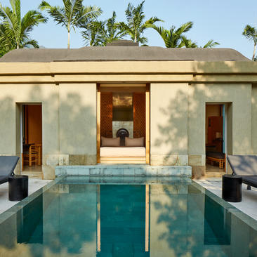 Garden pool suite with symmetrical reflecting pool at Amanjiwo, framed by pavilion with wooden doors and tropical foliage.
