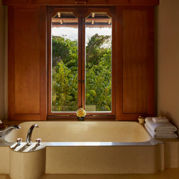 Suite bathtub at Amankila with dual doors opening to tropical garden views.
