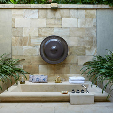 Outdoor bathtub at Amanjiwo with circular wall feature and potted plants on either side.