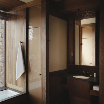 Bathroom at Amangani with dark wood finishes, walk-in shower, and natural light from windows.