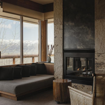 Spring Gulch Suite at Amangani featuring a wood-burning fireplace and window seating overlooking mountain views.