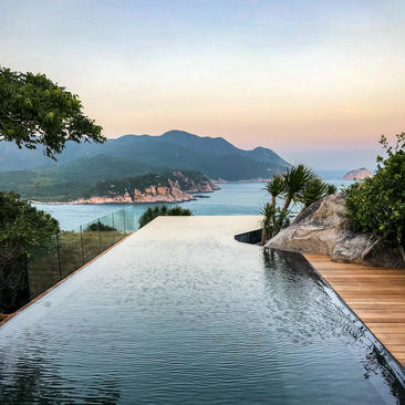 Ocean pool pavilion at Amanoi overlooking the bay at dawn, with mountains beyond.
