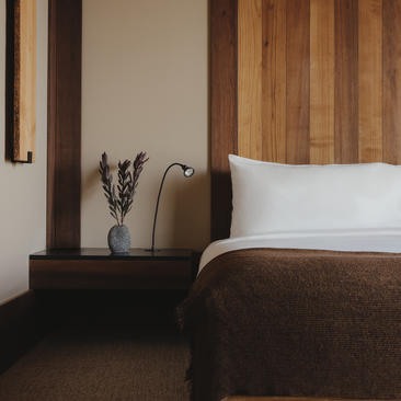 Principal bedroom in the Gros Ventre Suite at Amangani, featuring warm wood panelling and a bedside arrangement with fresh lavender.