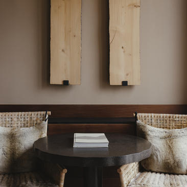 Shoshone Suite bedroom with two wooden wall sconces above a black bedside table at Amangani.