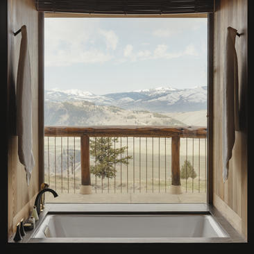 View from an open door at Amangani towards snow-capped mountains and forested valleys below.