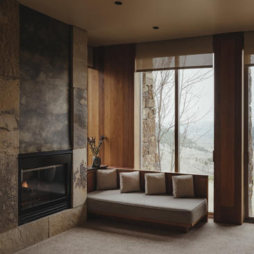 Principal bedroom with fireplace, window seating and forest views at Amangani.
