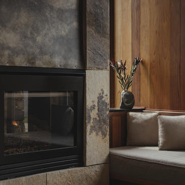 Fireplace with dark surround beside a sofa at Amangani, with dried flowers in a vase on the mantelpiece.