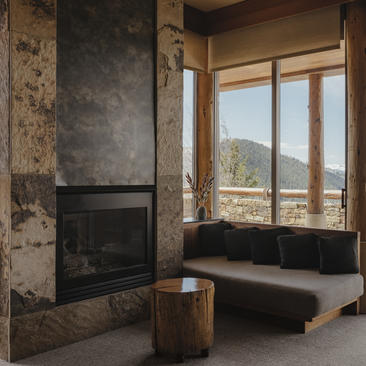 Fireplace with stone surround and window seat overlooking mountains at Amangani.