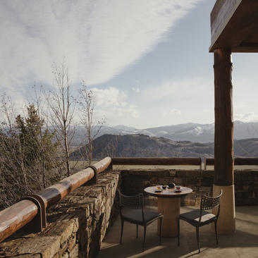 Wooden deck at Amangani with mountain views, featuring a fire pit and rustic seating overlooking distant peaks.