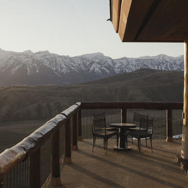 Wooden deck at Amangani with dining table overlooking snow-capped mountains.