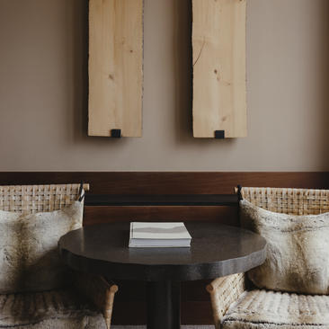 Principal bedroom with dark wooden bedside table and woven cushions at Amangani.